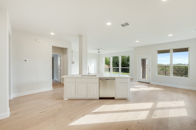 kitchen with an island with sink, light hardwood / wood-style floors, a healthy amount of sunlight, and dishwasher