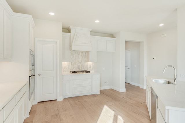 kitchen with white cabinetry, appliances with stainless steel finishes, sink, and light hardwood / wood-style floors