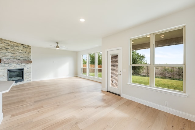 unfurnished living room featuring a fireplace, light hardwood / wood-style floors, and ceiling fan