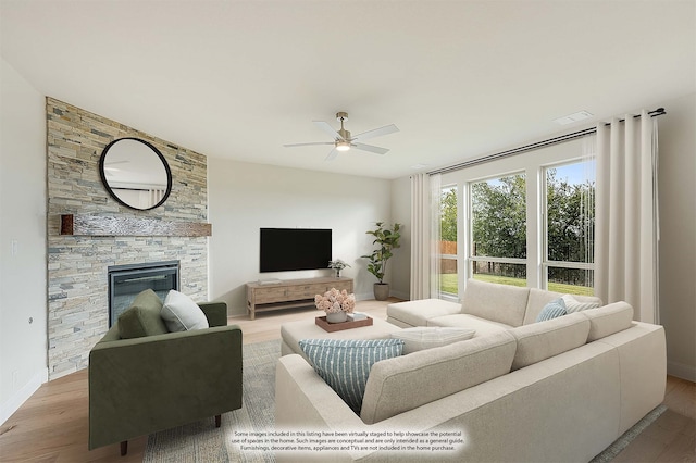 living room with light wood-type flooring, ceiling fan, and a fireplace