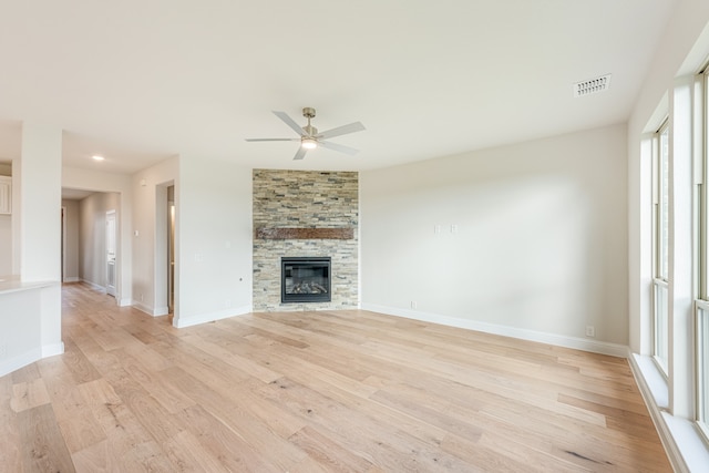 unfurnished living room featuring a large fireplace, light hardwood / wood-style floors, and ceiling fan