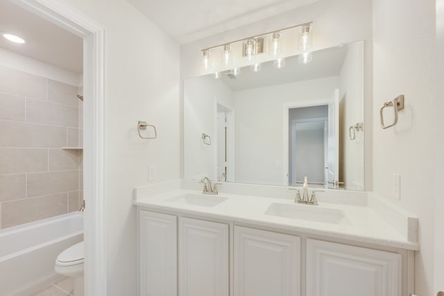 full bathroom with toilet, tiled shower / bath combo, vanity, and tile patterned floors