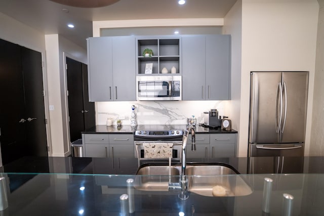 kitchen with gray cabinetry, stainless steel appliances, and tasteful backsplash