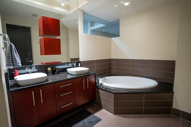 bathroom featuring tile patterned floors, vanity, and tiled bath