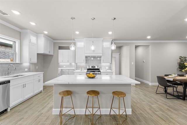 kitchen featuring appliances with stainless steel finishes, sink, tasteful backsplash, white cabinetry, and a center island