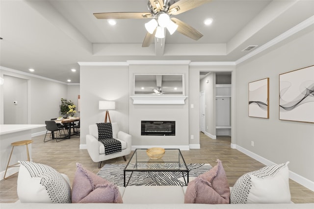 living room with a tray ceiling, ceiling fan, and light hardwood / wood-style floors