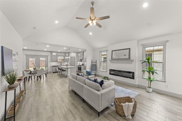 living room featuring ceiling fan, light hardwood / wood-style flooring, high vaulted ceiling, and french doors