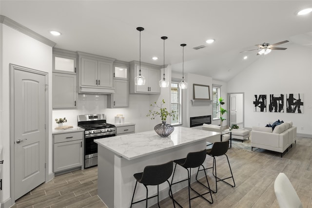 kitchen with a breakfast bar, light wood-type flooring, gas stove, and ceiling fan