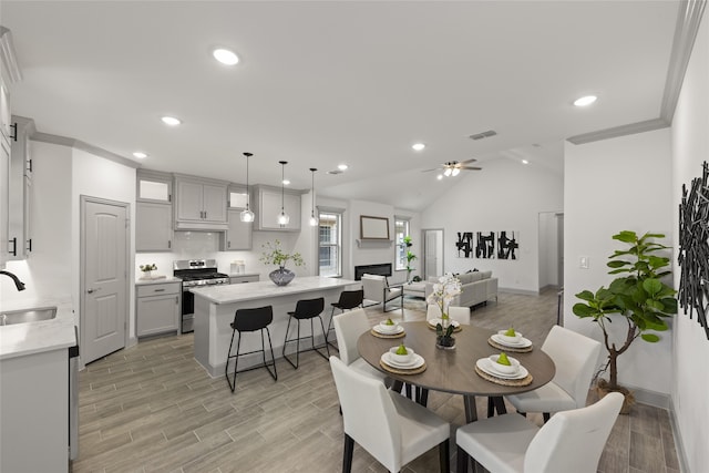 dining area featuring ceiling fan, lofted ceiling, sink, and light hardwood / wood-style floors