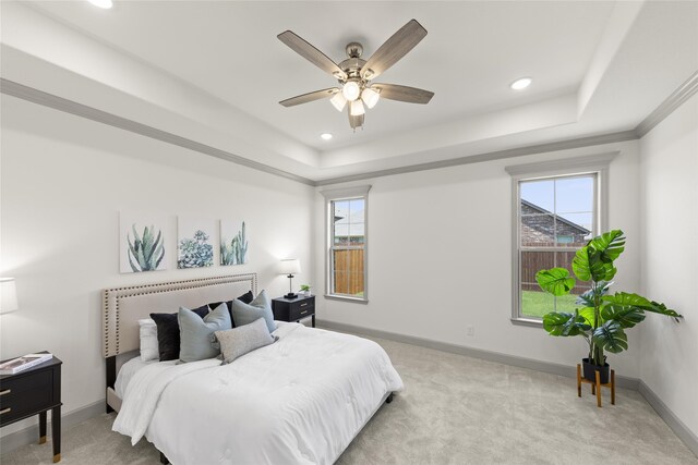 bedroom featuring ceiling fan, light carpet, and a tray ceiling