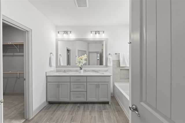 bathroom with a tub and double vanity