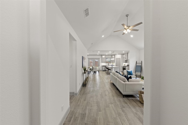 hallway featuring lofted ceiling and light hardwood / wood-style flooring