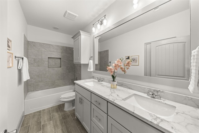 full bathroom featuring dual vanity, toilet, and tiled shower / bath combo