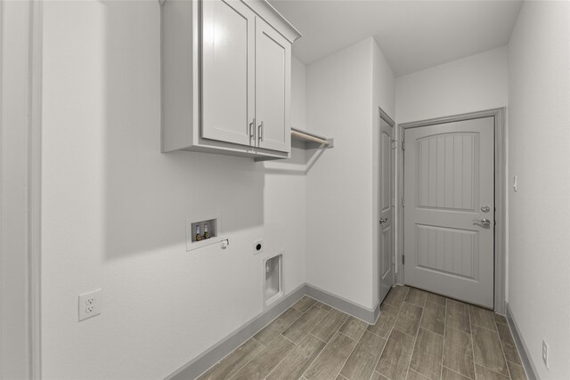 washroom featuring electric dryer hookup, hookup for a washing machine, cabinets, and light hardwood / wood-style floors