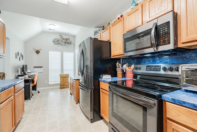 kitchen with appliances with stainless steel finishes and vaulted ceiling