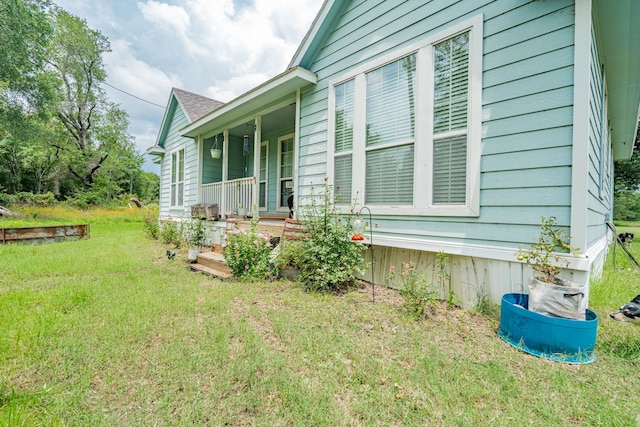 view of home's exterior with covered porch and a yard