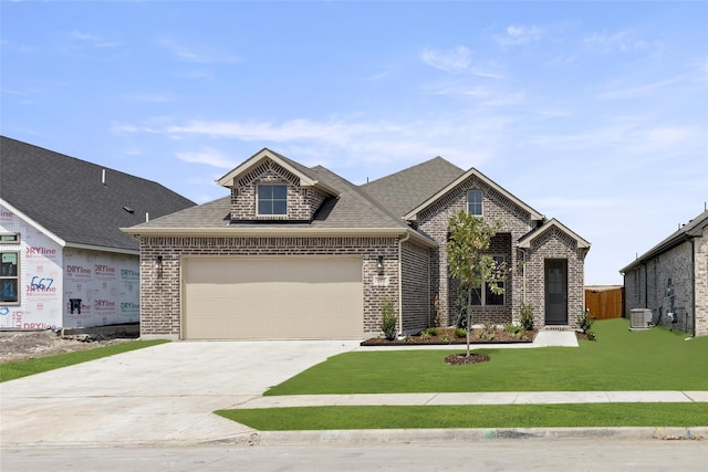 view of front of home featuring cooling unit, a front yard, and a garage