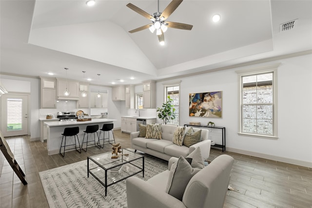 living room featuring plenty of natural light, ceiling fan, sink, and high vaulted ceiling