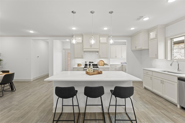 kitchen featuring decorative light fixtures, appliances with stainless steel finishes, light hardwood / wood-style floors, and sink