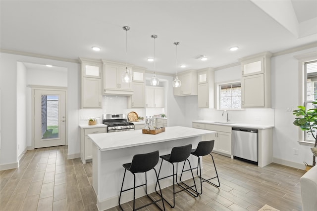 kitchen featuring white cabinets, decorative light fixtures, light wood-type flooring, appliances with stainless steel finishes, and a kitchen island