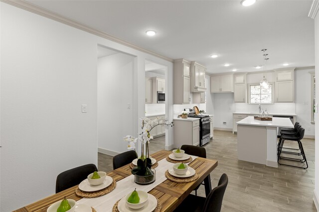 dining space with crown molding, sink, and light wood-type flooring