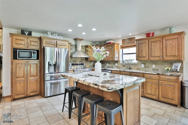 kitchen featuring a kitchen island, tasteful backsplash, wall chimney exhaust hood, appliances with stainless steel finishes, and sink