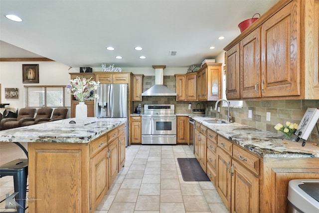 kitchen featuring stainless steel appliances, light tile flooring, a kitchen island, backsplash, and wall chimney exhaust hood