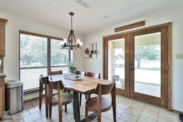 tiled dining space with a chandelier and french doors