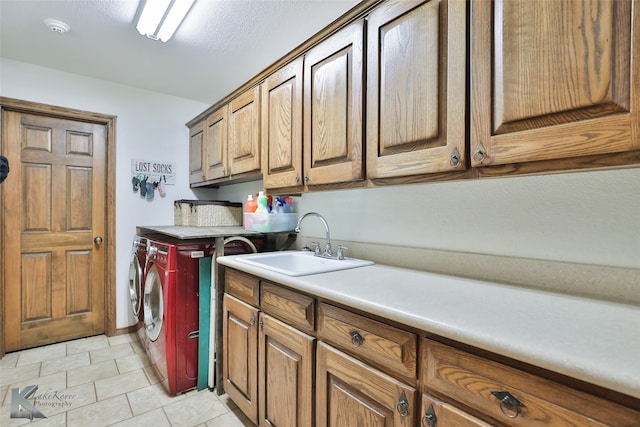 washroom featuring independent washer and dryer, sink, light tile flooring, and cabinets