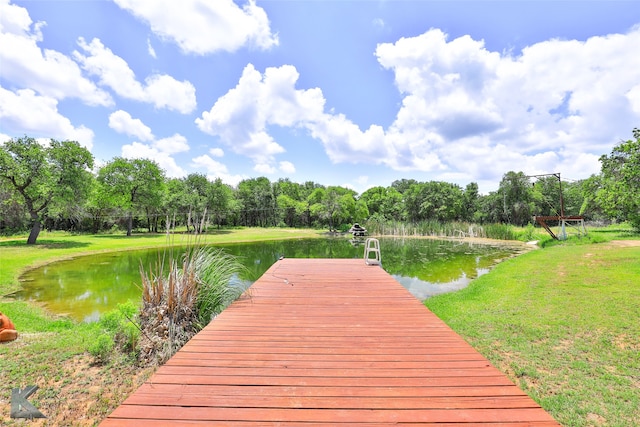 dock area with a lawn and a water view