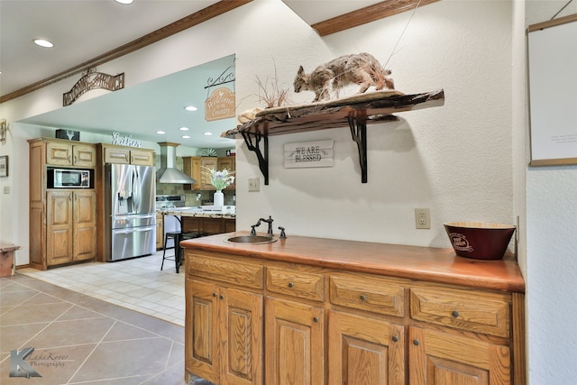 kitchen with stainless steel refrigerator with ice dispenser, built in microwave, wall chimney exhaust hood, sink, and light tile floors