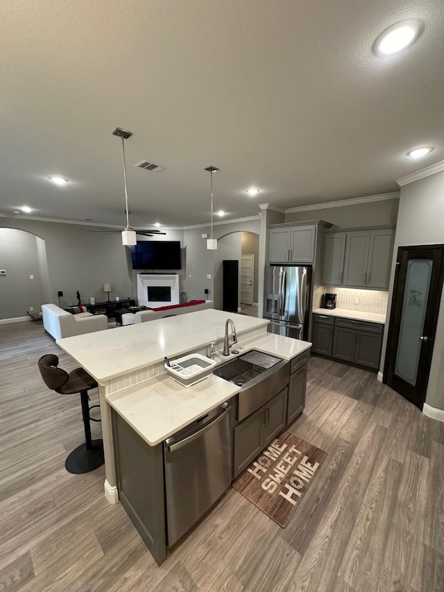 kitchen with a large island, gray cabinets, appliances with stainless steel finishes, pendant lighting, and sink