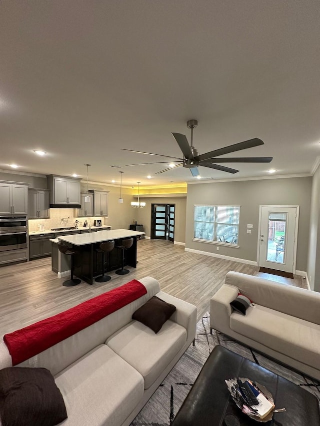 living room featuring light wood-type flooring, ceiling fan, and crown molding