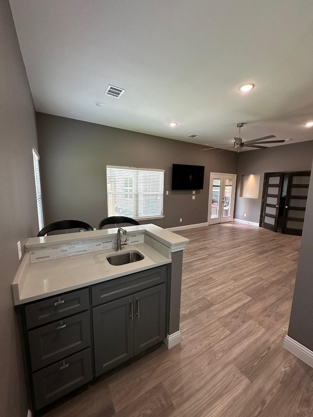 kitchen featuring a wealth of natural light, gray cabinetry, ceiling fan, wood-type flooring, and sink