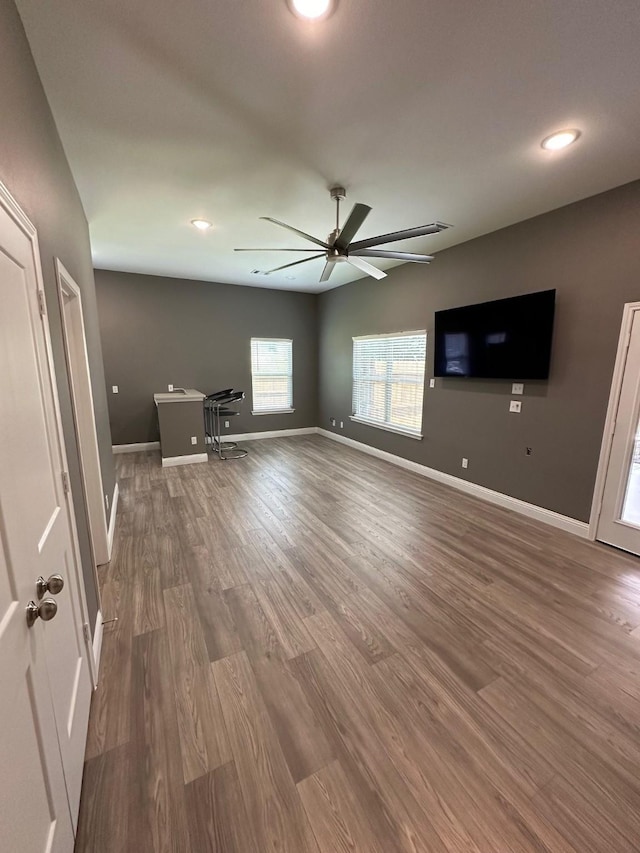 unfurnished living room with ceiling fan and dark wood-type flooring