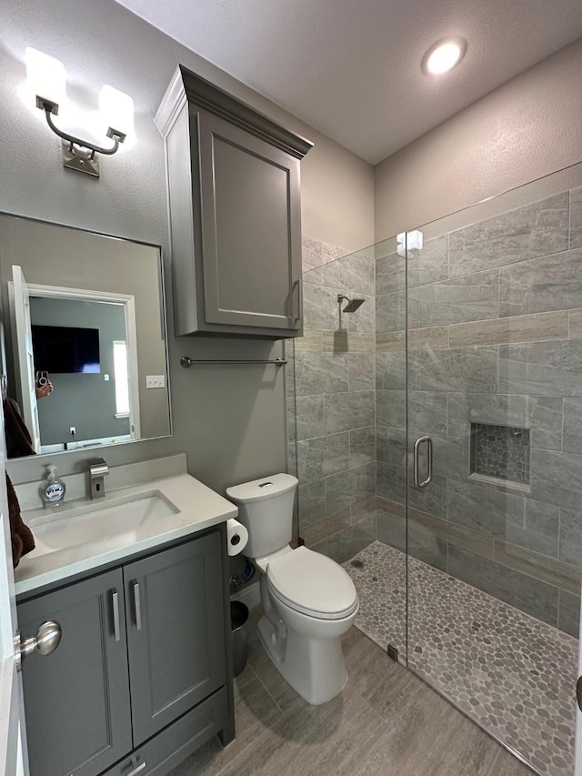 bathroom featuring hardwood / wood-style floors, an enclosed shower, vanity, and toilet