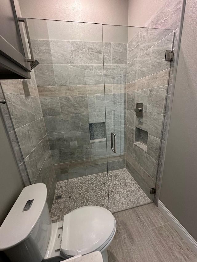 bathroom featuring toilet and an enclosed shower