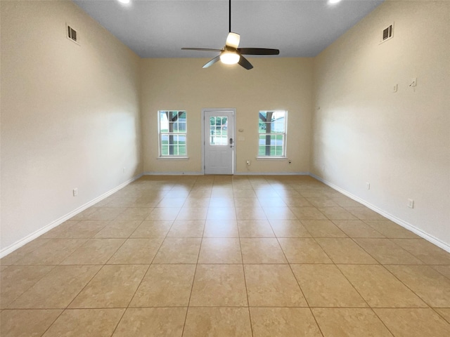 spare room with ceiling fan, a towering ceiling, and light tile patterned flooring