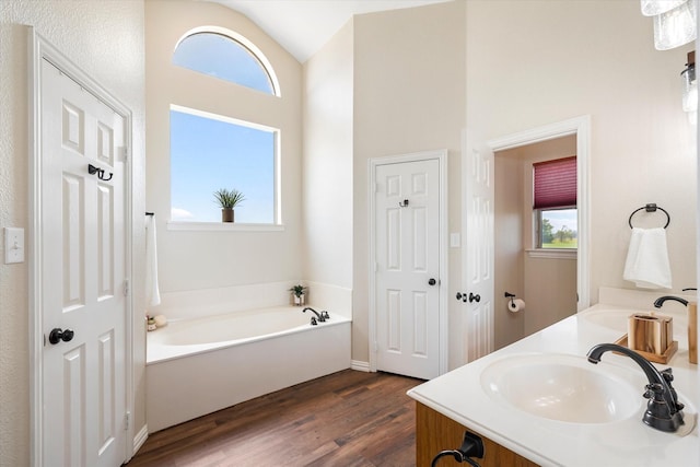 bathroom with a tub to relax in, vanity, hardwood / wood-style floors, and lofted ceiling