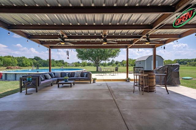 view of patio featuring outdoor lounge area, an outdoor bar, ceiling fan, and a storage shed