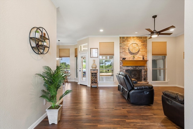 living room featuring dark hardwood / wood-style floors, a brick fireplace, ceiling fan, and ornamental molding