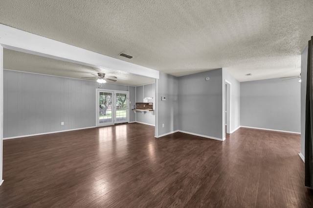 unfurnished living room with dark hardwood / wood-style floors, ceiling fan, and a textured ceiling