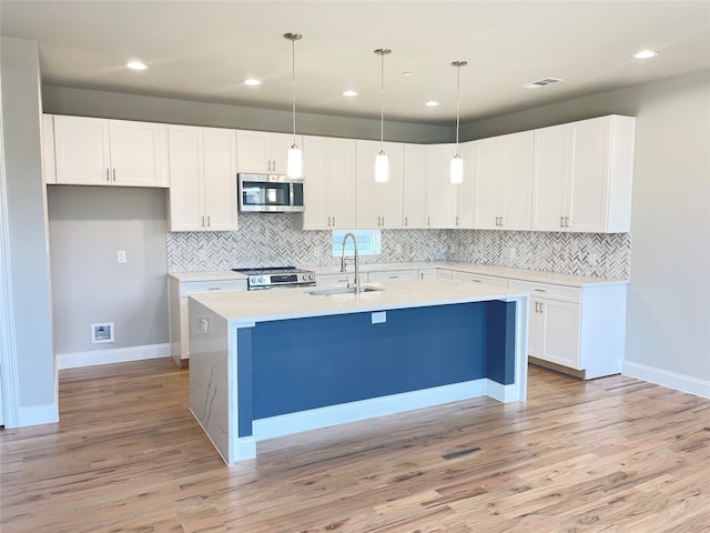 kitchen with stainless steel appliances, white cabinetry, light wood-type flooring, and sink