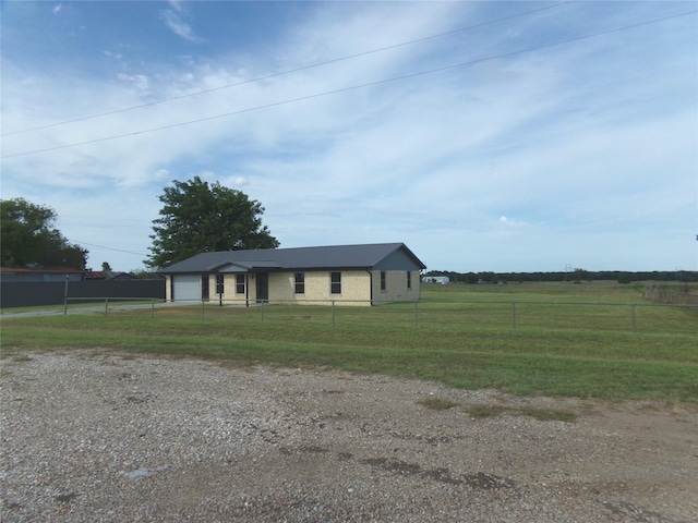 view of front of house with a garage, a front yard, and a rural view