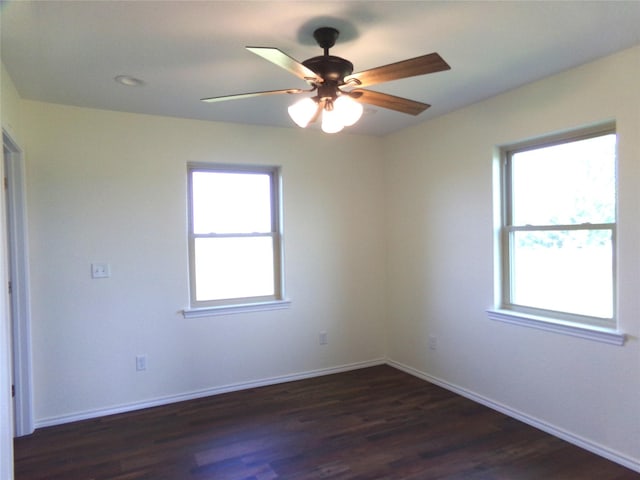 spare room with dark hardwood / wood-style floors, a wealth of natural light, and ceiling fan