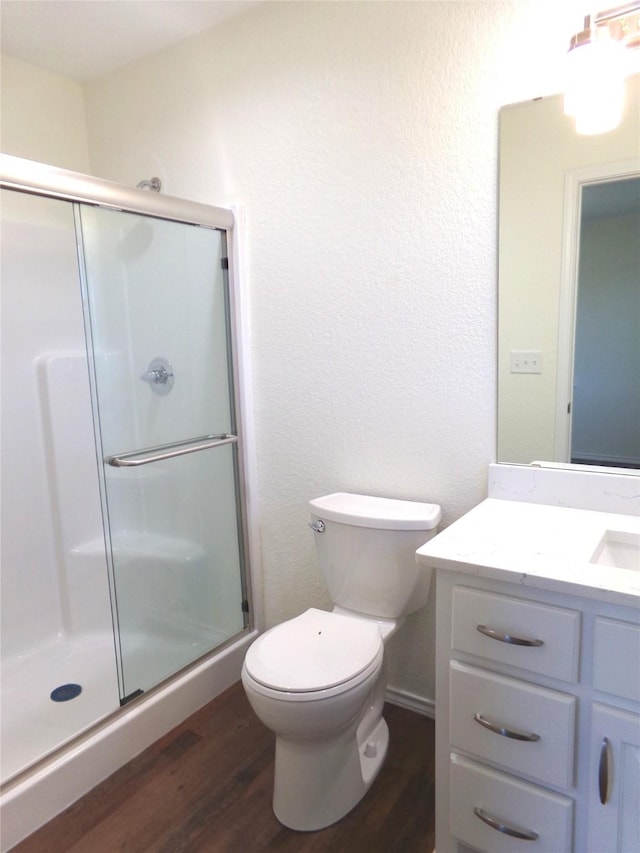 bathroom featuring wood-type flooring, a shower with shower door, and toilet