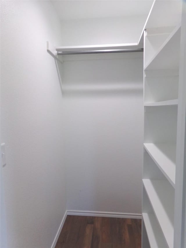 walk in closet with dark wood-type flooring