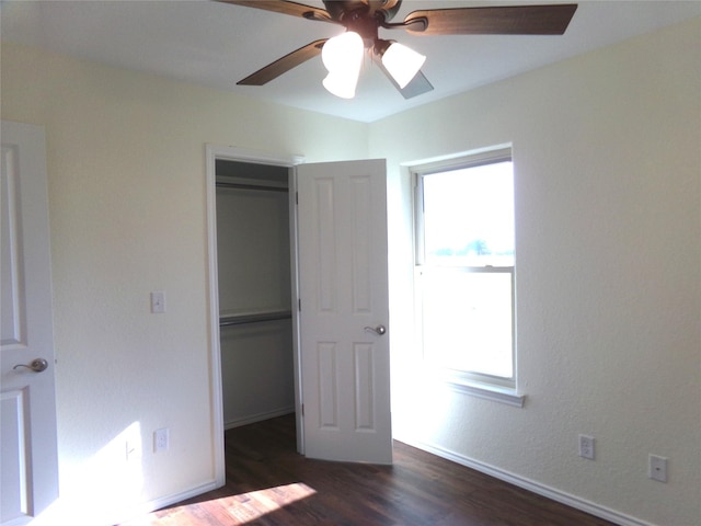 unfurnished bedroom featuring multiple windows, a closet, dark hardwood / wood-style floors, and ceiling fan