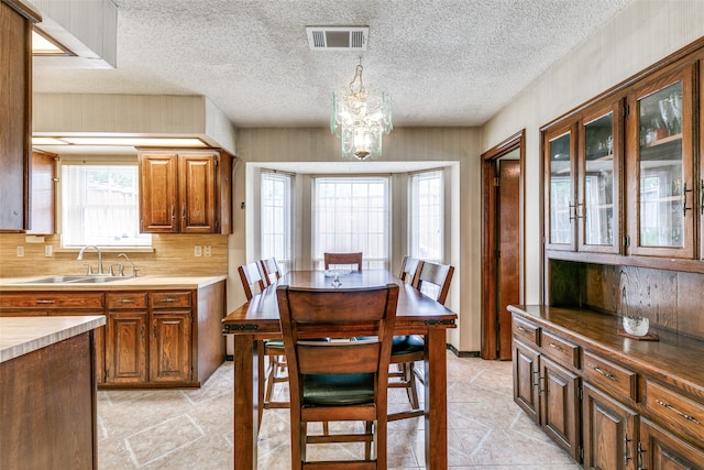 dining room featuring sink, a chandelier, and a textured ceiling