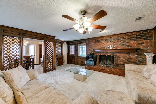 carpeted living room with a textured ceiling, brick wall, ceiling fan, and a brick fireplace